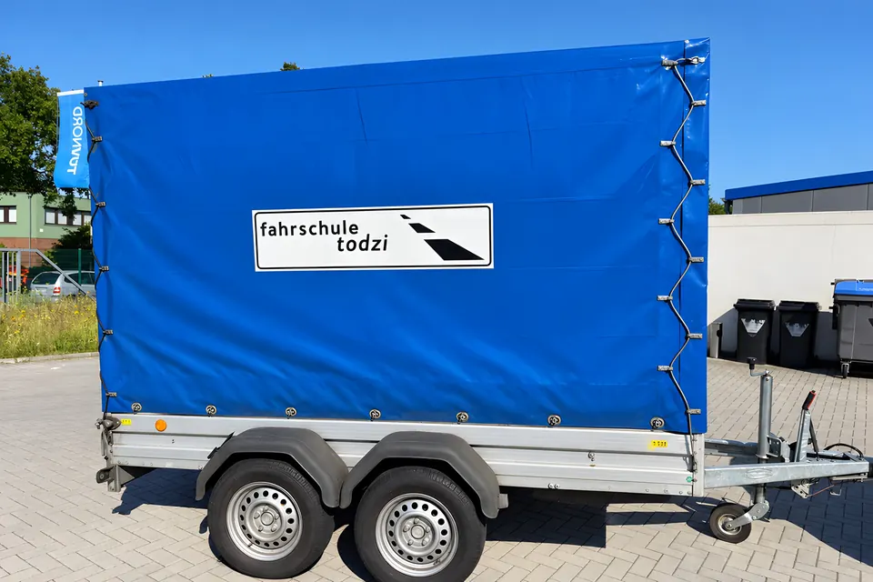 Blauer Doppelachs-Kofferanhänger mit Logo der Fahrschule Todzi