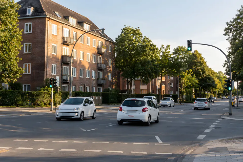Stimmungsbild: Straßenkreuzung mit Ampel, Backsteinhaus und Autos im Abendlicht